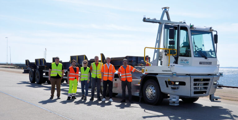 The project group standing beside the equipped terminal tractor at a quay