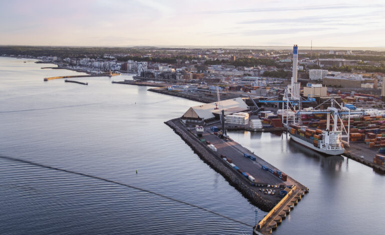 Vy över del av containerterminal med stadsmiljö i bakgrunden